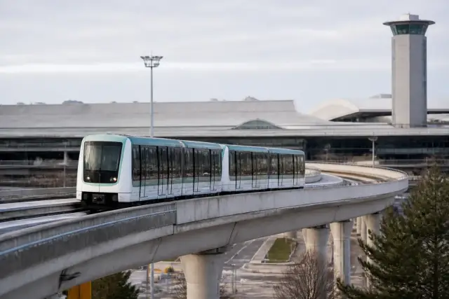 Rame de métro automatique blanche sur une voie surélevée, ciel bleu pâle, aucun voyageur visible