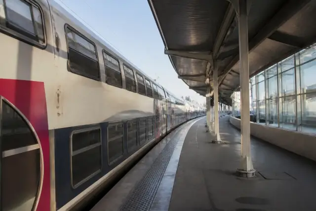 Train de banlieue à quai dans une gare, vu depuis le bord du quai