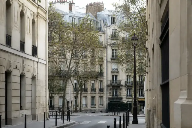 Rue animée d’un quartier de l’est de Paris avec immeubles en pierre et arbres d’alignement