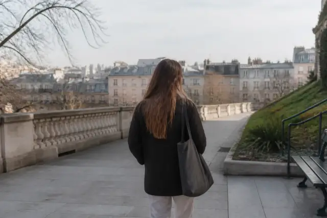 Une large esplanade dallée bordée de balustrades et de jardins en pente, lumière du matin, quelques silhouettes lointaines sans visage net