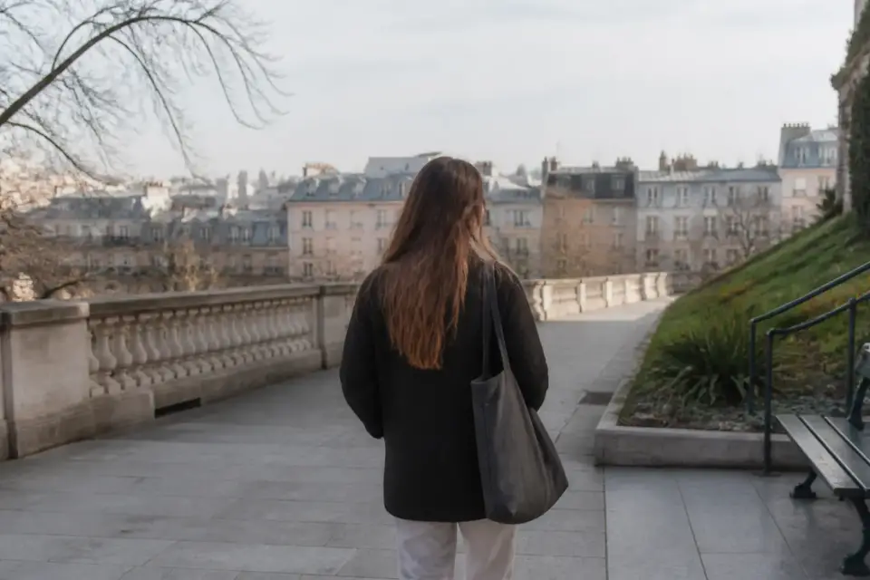 Une large esplanade dallée bordée de balustrades et de jardins en pente, lumière du matin, quelques silhouettes lointaines sans visage net