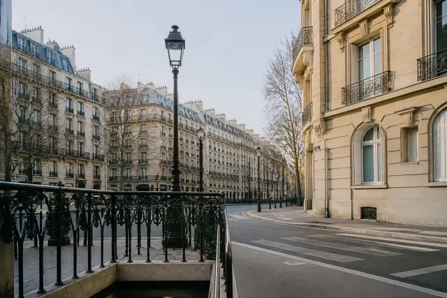 Rue parisienne à façades claires avec une entrée de métro au coin