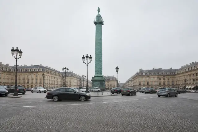Grande place parisienne avec colonne centrale et circulation autour