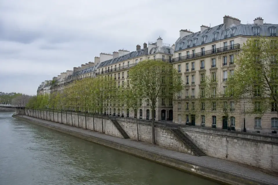 Quai de Seine bordé d’immeubles de pierre et d’arbres, vu depuis un pont