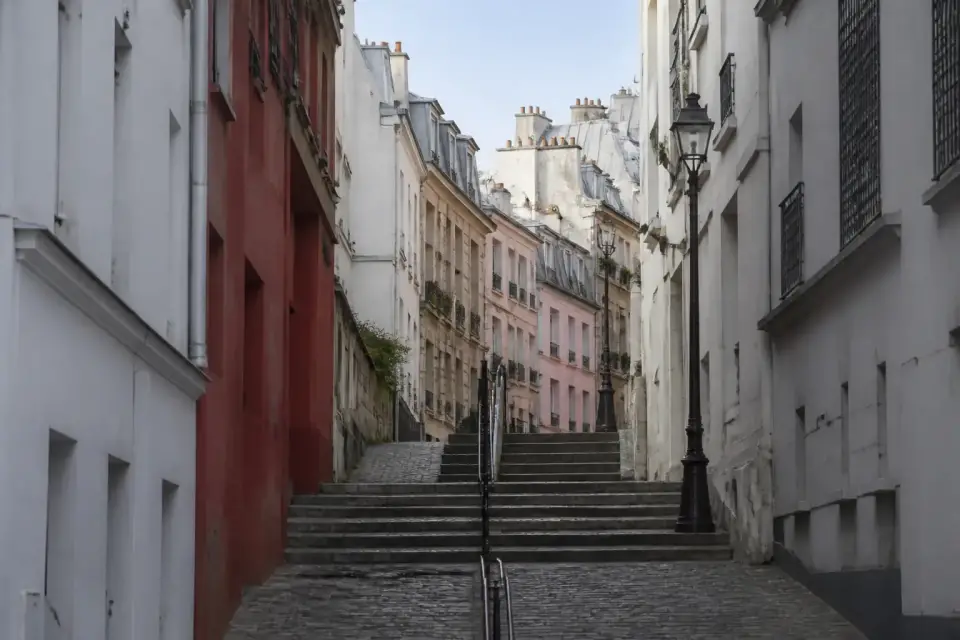 Escalier étroit et rue pavée montant entre des façades blanches et colorées