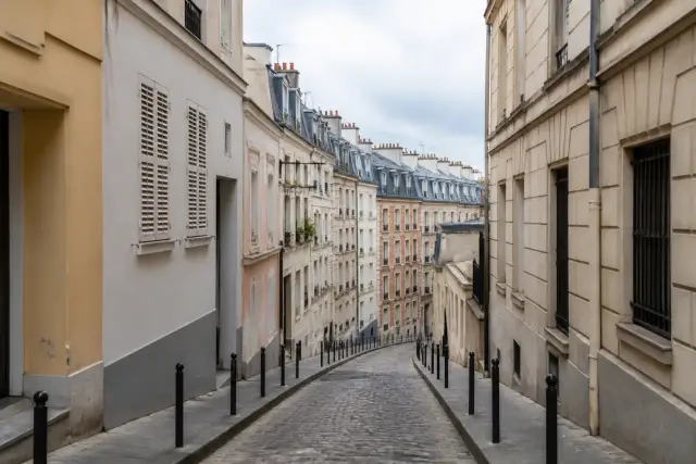 Rue en pente bordée de petits immeubles et de façades colorées dans le sud de Paris